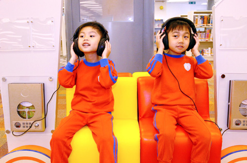 小朋友全神貫注地使用大埔公共圖書館的音響設備。
