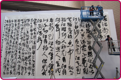 文物修復辦事處為各類專題展覽提供技術支援。圖中文物修復專家在香港文化中心懸掛大型字畫。