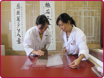 Conservation volunteers help with the lining of a Chinese calligraphy piece.