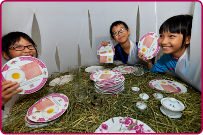 Young visitors enjoying a table setting at the Sparkle! Art for the Future exhibition.