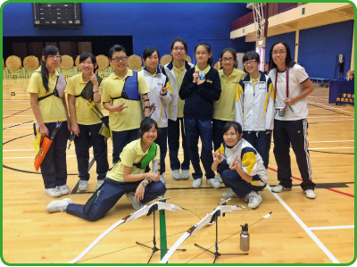 A School Sports Programme Coordinator (back row, far right) leads students in an archery activity.